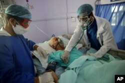 Medical workers attend to a COVID-19 patient in an intensive care unit at a hospital in Sanaa, Yemen, June 14, 2020.