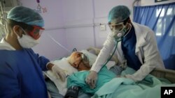 Medical workers attend to a COVID-19 patient in an intensive care unit at a hospital in Sanaa, Yemen, June 14, 2020.