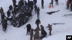 Emergency service members dig in the snow around at least three overturned vehicles, near the town of Bahcesehir, in Van province, eastern Turkey, Feb. 5, 2020.