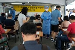 A medical worker guides people as they wait to get coronavirus testing at a public health center in Seoul, South Korea, July 14, 2021.