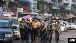 police march with a resident arrested during a crackdown on protesters
