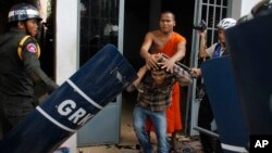 A Cambodian Buddhist monk, center top, helps an injured worker, center bottom, beaten by riot police inside a Buddhist pagoda in Phnom Penh, Cambodia, Tuesday, Nov. 12, 2013. Cambodian police have fired live ammunition at protesting garment workers outside the capital, injuring at least six protesters and killing a bystander. The human rights group Licadho says hundreds of workers from the SL Garment Processing (Cambodia) Ltd. Factory clashed Tuesday with about 1,000 riot police sent to block a march from the factory to the Phnom Penh residence of Prime Minister Hun Sen. (AP Photo)