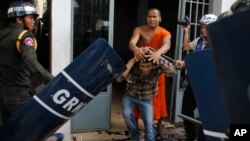 A Cambodian Buddhist monk, center top, helps an injured worker, center bottom, beaten by riot police inside a Buddhist pagoda in Phnom Penh, Cambodia, Tuesday, Nov. 12, 2013. Cambodian police have fired live ammunition at protesting garment workers outside the capital, injuring at least six protesters and killing a bystander. The human rights group Licadho says hundreds of workers from the SL Garment Processing (Cambodia) Ltd. Factory clashed Tuesday with about 1,000 riot police sent to block a march from the factory to the Phnom Penh residence of Prime Minister Hun Sen. (AP Photo)