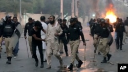 Police detain a supporter of the Tehreek-e-Labbaik Pakistan party during clashes with its members in Karachi, Pakistan, Oct. 13, 2024.