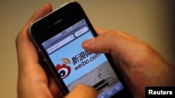 FILE - A man holds an iPhone as he visits the Sina Weibo microblogging site (China's version of Twitter) in Shanghai.