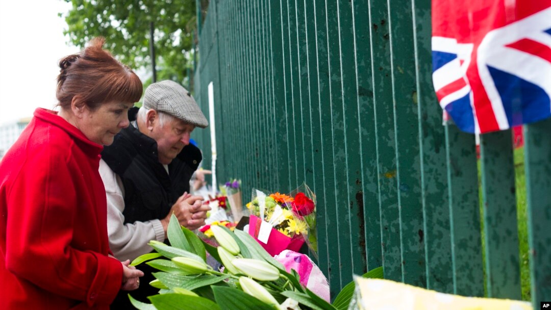 Pasangan Inggris berdoa di luar barak Woolwich, London (24/5), untuk tentara Inggris yang dibunuh sehari sebelumnya di jalan dekat barak. (AP/Bogdan Maran)