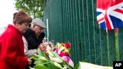 Pasangan Inggris berdoa di luar barak Woolwich, London (24/5), untuk tentara Inggris yang dibunuh sehari sebelumnya di jalan dekat barak. (AP/Bogdan Maran)