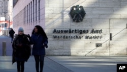 FILE - People walk past the German Foreign Ministry building in Berlin, Germany, March 1, 2018.