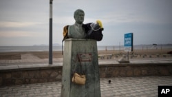 A face shield and a couple of backpacks sit on a bust on the beach amid the new coronavirus pandemic in Chorrillos, Lima, Peru, Jan. 26, 2021
