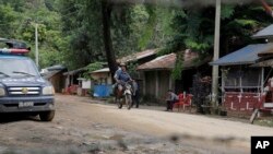 Local residents ride a motorcycle past a police checkpoint in Myanmar's border town of Maungdaw, Rakhine State, Oct. 13, 2016.