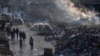 Palestinians walk past a pile of burning garbage in Gaza City, Feb. 12, 2025. 