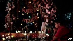 A child prays in front a street altar near a collapsed building in Amsterdam Street in the Condesa neighborhood of Mexico City, Sept. 24, 2017.