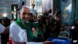 Un hombre vota en las elecciones presidenciales anticipadas en Irán mientras sostiene una foto del difunto presidente Ebrahim Raisi, en un centro de votación en Teherán, Irán, el 28 de junio de 2024.