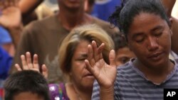 In this March 11, 2018 photo, a tear runs down the cheek of Venezuelan woman praying during religious service in Simon Bolivar Square where many are living in tents in Boa Vista, Roraima state, Brazil. 