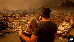 Megan Mantia, kiri, dan pacarnya Thomas, mengunjungi puing-puing rumah Mantia yang musnah dilalap oleh kebakaran hutan di Altadena, California, 8 Januari 2025.