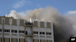 Para penyintas menunggu regu penyelamat di balkon gedung berlantai sembilan, kantor perusahaan telepon milik pemerintah di Mumbai, India, saat terjadi kebakaran di gedung tersebut, Senin, 22 Juli 2019. (AP Photo / Rafiq Maqbool)