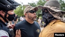 Dos manifestantes en una protesta contra el mandato de usar mascarillas durante la pandemia, en Austin, Texas en junio pasado.