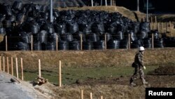 A man walks near waste containing radiated soil, leaves and debris from the decontamination operation at a storage site at Miyakoji area in Tamura, Fukushima prefecture, April 1, 2014. 