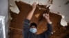 FILE - A contractor removes material from a ceiling in a recently purchased home that sustained water damage because of broken pipes, which froze during an unprecedented winter storm, in Houston, Texas, Feb, 19, 2021.