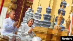 Cambodia's King Norodom Sihamoni (L) and Queen mother Norodom Monineath Sihanouk sit on the royal float as they transport urns with some of the cremains of former late King Norodom Sihanouk from a crematorium to the Royal Palace in Phnom Penh February 7, 2013. Some of Sihanouk's ashes were scattered near the confluence of the four rivers in Phnom Penh on Tuesday, while others were put in three urns, which, according to his wishes, will be placed on the grounds of the royal palace, media reported.