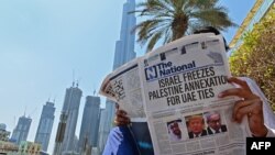 14일 두바이에서 한 주민이 이스라엘과 아랍에미리트 관계 정상화 합의 소식이 머리기사로 실린 신문을 읽고 있다.