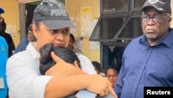 La ministra de Educación de Guyana, Priya Manickchand, consuela a uno de los padres de uno de varios niños que murieron en el incendio de un dormitorio de una escuela secundaria, en Mahdia, Guyana, mientras el primer ministro Mark Phillips observa.