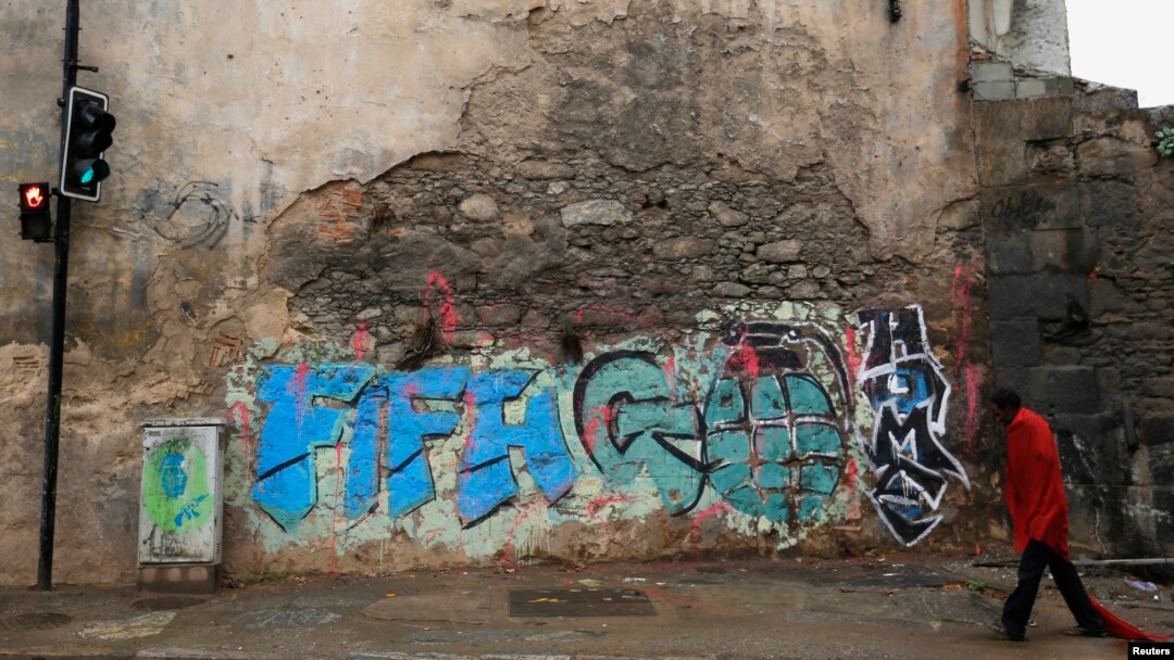 Seorang pria tunawisma melewati grafiti bertuliskan "FIFA pulanglah" di Rio de Janeiro (28/5). (Reuters/Sergio Moraes)
