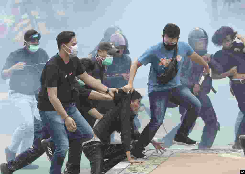 Through tear gas clouds, plain-clothed police officers detain protesters during a rally in Jakarta, Indonesia.