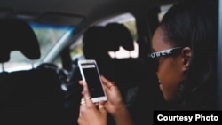 FILE - A passenger uses her smartphone during an Uber ride.