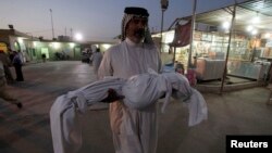 An Iraqi man carries the body of his son, who was killed by a car bomb attack, during a funeral in Najaf, south of Baghdad, Aug. 15, 2013. 