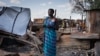A woman from Murle ethnic group stands at her burnt tea shop in a market in Gumuruk, South Sudan, on June 10, 2021. The village was attacked by an armed youth group. 