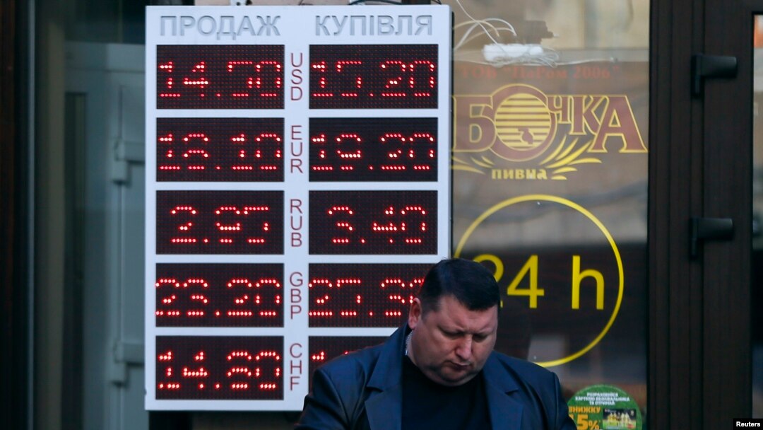 Seorang pria membaca koran di depan kantor penukaran mata uang di Kyiv (10/11). (Reuters/Gleb Garanich)