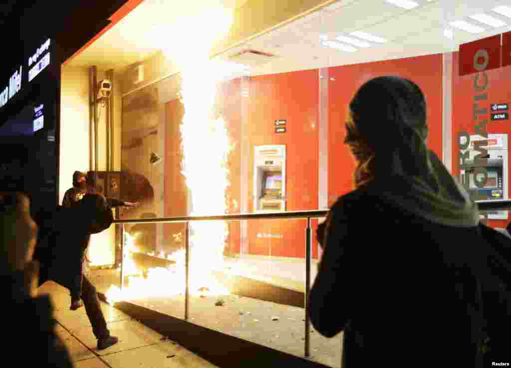 A demonstrator throws a firebomb at the windows of an ATM facility during a protest in support of the 43 missing trainee teachers in Mexico City.