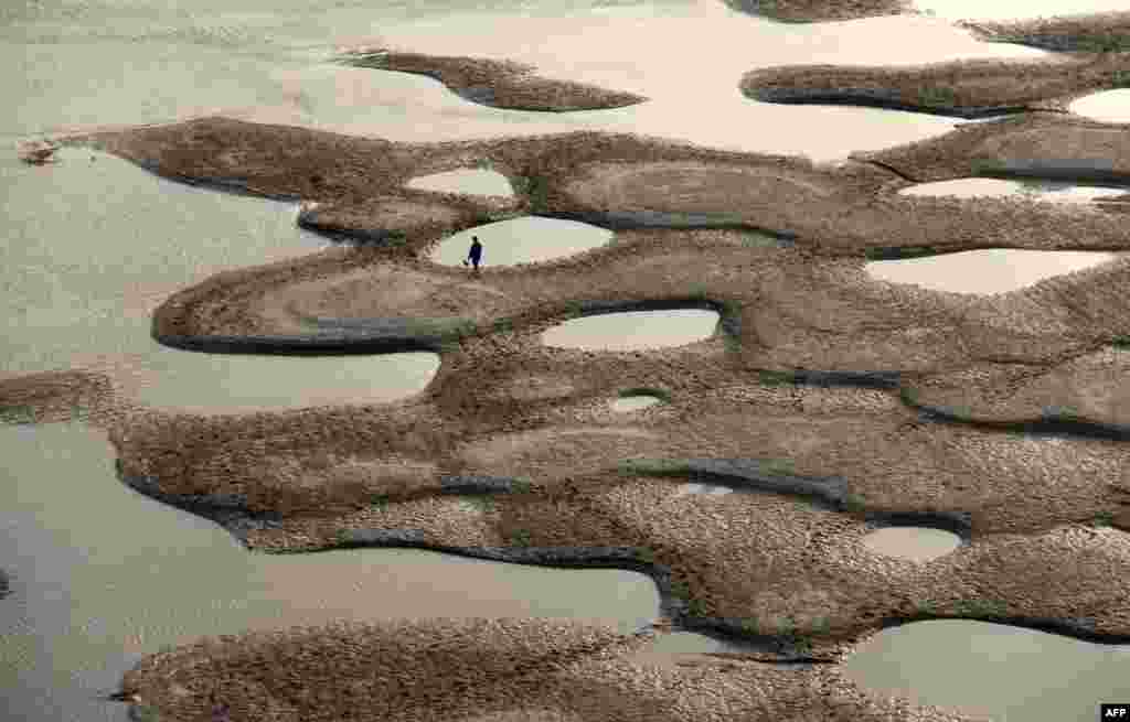 A man walks along the riverbed of the Hanjiang River during its dry season in Shiyan, central China&#39;s Hubei province, Apr. 9, 2013. 