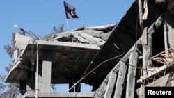 Un drapeau du groupe Etat islamique flottant au-dessus des ruines d'une maison de Raqqa, ex-capitale de l'organisation en Syrie, le 18 octobre 2017.