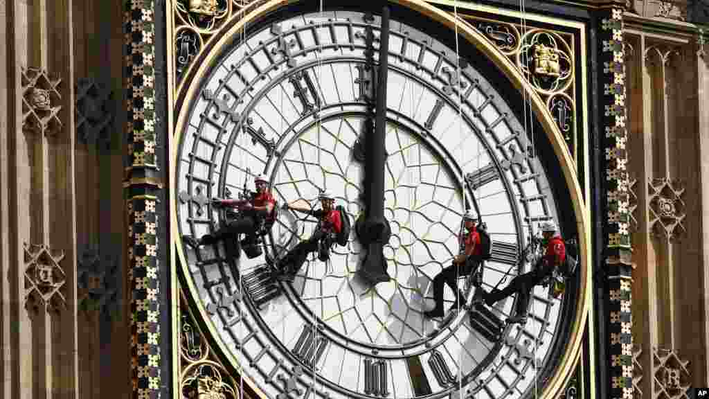 Des travailleurs suspendus&nbsp;à côté du cadran de l'horloge alors qu'ils nettoient la tour de l'horloge Big Ben de la Maison du Parlement à Londres, le lundi 18 août 2014.