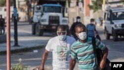 En esta imagen de marzo, se ve a dos ciudadanos haitianos caminando con sus máscaras cerca del ccentro de Puerto Príncipe.