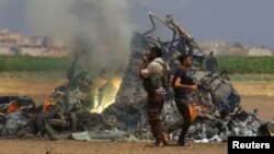 Men inspect the wreckage of a Russian helicopter that had been shot down in the north of Syria's rebel-held Idlib province, Syria August 1, 2016. 