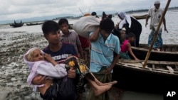 Pripadnik Rohindža manjine iznosi staricu iz čamca kojim su prešli reku pošto su iz Mjanmara prebegli u Bangladeš, 2. septembar 2017.