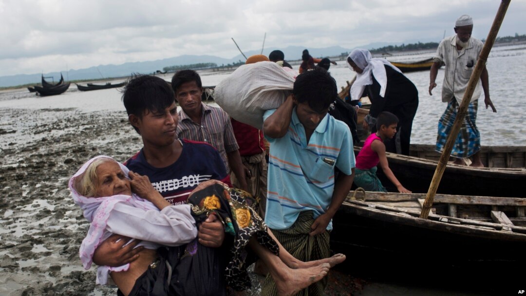 A Rohingya ethnic minority from Myanmar carries an elderly woman as they alight from a local boat on which they crossed a river, after crossing over to the Bangladesh side of the border near Cox's Bazar's Dakhinpara area, Saturday, Sept. 2, 2017.
