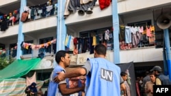 Workers of the United Nations Relief and Works Agency for Palestine Refugees talk in the playground of a school that has been converted into a shelter for displaced Palestinians in Khan Yunis, Oct. 25, 2023, 