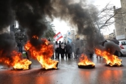 Relatives of victims of the Beirut port explosion burn tires during a protest, after a Lebanese court removed the judge leading the investigation into the explosion, outside the Justice Palace in Beirut, Lebanon, Feb. 19, 2021.