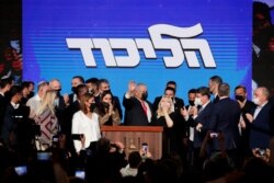 Israeli Prime Minister Benjamin Netanyahu, center, with his party members waves to his supporters after the first exit poll results for the Israeli parliamentary election at his Likud party's headquarters in Jerusalem, March. 24, 2021.