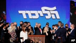 Israeli Prime Minister Benjamin Netanyahu, center, with his party members waves to his supporters after the first exit poll results for the Israeli parliamentary election at his Likud party's headquarters in Jerusalem, March. 24, 2021.