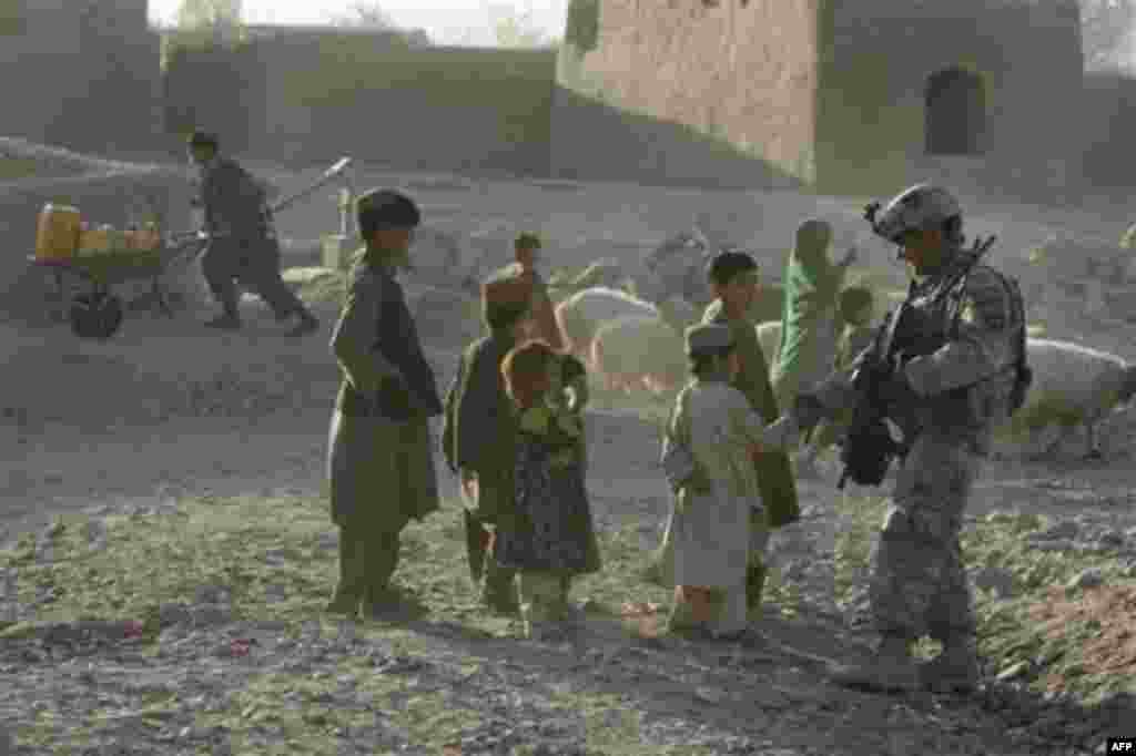 A US Army soldier from First Battalion, 502nd Infantry Regiment, 101st Airborne Division shakes hands with an Afghan boy diring a foot patrol in East Now Ruzi village, district Panjwai, Afghanistan, Monday, Nov. 22, 2010.(AP Photo/Alexander Zemlianichenko