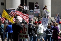 FILE - Demonstrators gather outside of the Ohio Statehouse to protest the stay-at-home order that is in effect until May 1, in Columbus, Ohio, April 20, 2020.