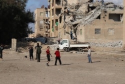 Displaced children play near buildings that were once housing for Islamic State fighters, in Raqqa, Syria, Feb. 23, 2020. In recent months, the partially destroyed buildings have become housing for families fleeing Idlib. (Heather Murdock/VOA)