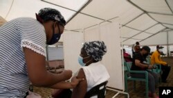 A woman receives a dose of a COVID-19 vaccine at a vaccine center, in Soweto, South Africa, Nov. 29, 2021. 