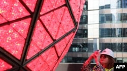 A woman takes a photo on Dec. 27, 2024, as the Times Square New Year's Eve Ball is unveiled in advance of the New Year celebration in New York City. The Waterford Crystal ball features more than 32,000 LED lights. 