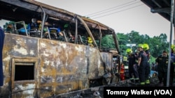 Authorities and firefighters work to remove bodies from the charred bus after a fiery crash that killed 22 students and three teachers, in suburban Bangkok, Oct. 1, 2024.